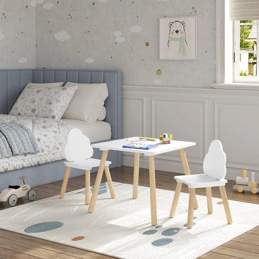 A set consisting of a rectangular children's table and two chairs with white backrests and solid wood legs, placed in a room with a bed and a wall drawing in the background.